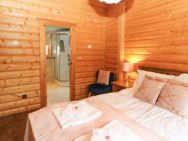 A bedroom with a bed pillows lamp chair and a door leading to a bathroom at Cornfield in Northallerton