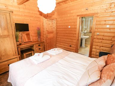 A bedroom with a bed towels on it a wooden wardrobe desk and a door leading to a bathroom at Cornfield in Northallerton