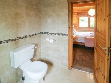 A bathroom with a toilet and tiled walls connected to a bedroom with a bed and window at Cornfield in Northallerton