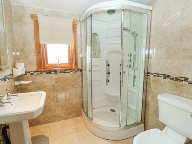A bathroom with a corner shower unit a toilet and a sink at Cornfield in Northallerton