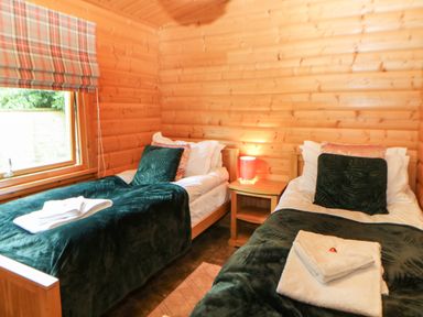 A bedroom with two single beds green blankets and a wooden nightstand with a lamp at Cornfield in Northallerton