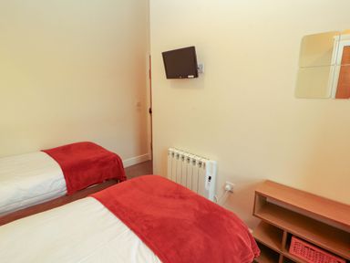 A bedroom with two beds and a television at The Old Bothy Bolton Low Houses near Wigton