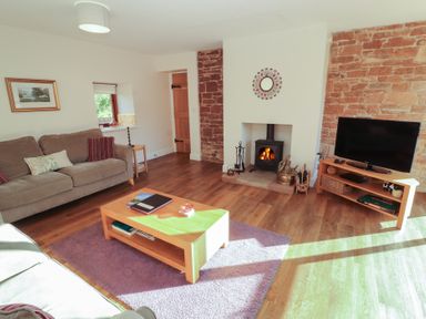 A living room with a sofa and a fireplace at The Old Grainstore Bolton Low Houses near Wigton