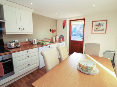 A kitchen with a dining table and chairs at The Old Grainstore Bolton Low Houses near Wigton
