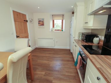 A kitchen with dining table and appliances at The Old Grainstore Bolton Low Houses near Wigton