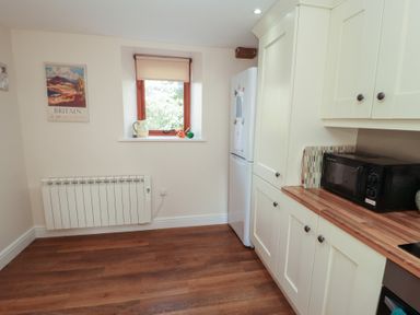 A kitchen with a microwave and refrigerator at The Old Grainstore Bolton Low Houses near Wigton