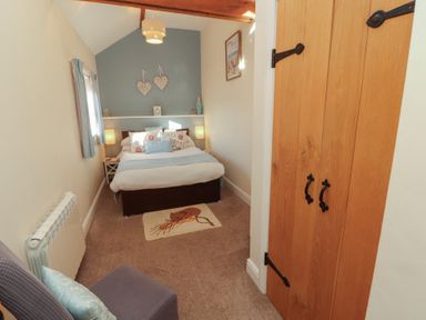 A bedroom with a bed and wardrobe at The Old Grainstore in Bolton Low Houses near Wigton