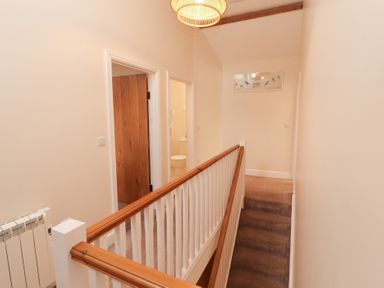 A hallway with a staircase and doors at The Old Grainstore Bolton Low Houses near Wigton
