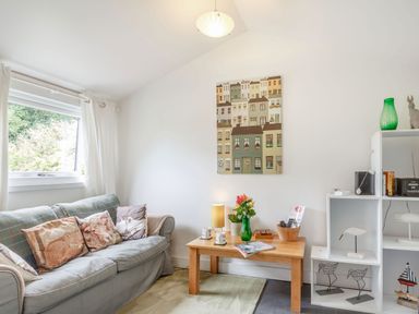 A living room with a sofa cushions coffee table and shelves with decorations at The Shepherd's Hut in Aberdovey