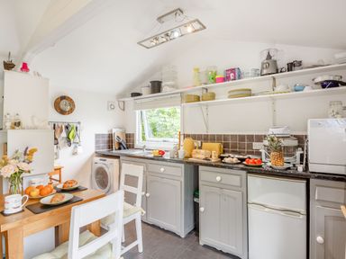 A kitchen with a wooden dining table and chairs and kitchen appliances at The Shepherd's Hut in Aberdovey