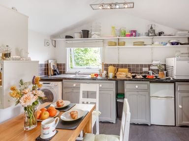 A kitchen with a wooden dining table set with croissants and fruit at The Shepherd's Hut in Aberdovey