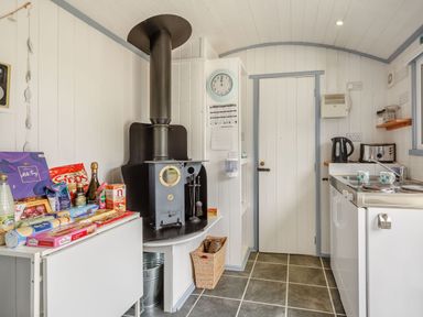 A kitchen with a black wood stove and snacks on a table at The Shepherd's Hut in Aberdovey
