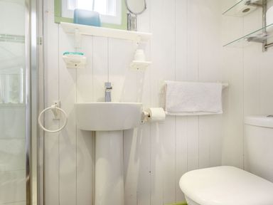 A bathroom with a pedestal sink a toilet a towel rack with a towel and a soap holder at The Shepherd's Hut in Aberdovey