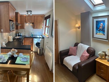A kitchen with wooden cabinets a black countertop and a dining table next to a living area with a brown armchair and framed artwork at Palmers Lodge in Egloskerry near Launceston