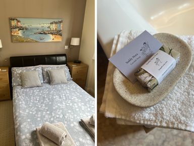 A bedroom with a double bed, bedside tables with lamps, and folded towels on the bed at Palmers Lodge in Egloskerry near Launceston