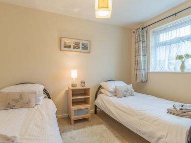 A bedroom with two single beds separated by a nightstand with a lamp and alarm clock at Crumstone Corner in Seahouses