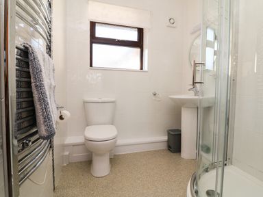 A bathroom with a toilet sink shower and towel rack at Honeysuckle Cottage in Bude