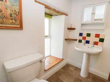 A bathroom with a toilet a pedestal sink and a window with wooden sill at The Farmhouse in Aberaeron