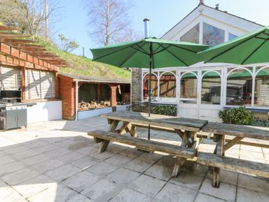 An outdoor patio area with picnic tables and green umbrellas at The Farmhouse in Aberaeron