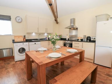 A kitchen with a dining table and appliances at Corner Barn Winterborne Stickland