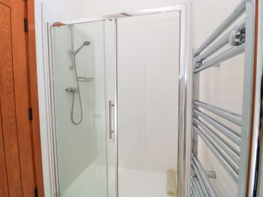 A shower with glass door and towel rail at Corner Barn Winterborne Stickland