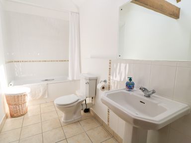 A bathroom with a bathtub, toilet, and sink at Corner Barn Winterborne Stickland