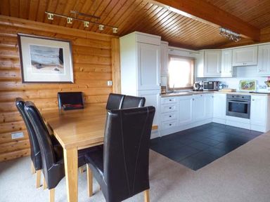 A kitchen and dining area with wooden dining table and black chairs at Ty Pren in Llanrhian near St Davids