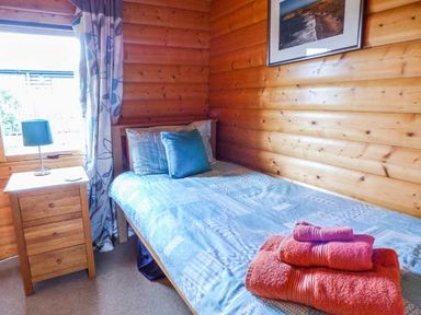 A small bedroom with a single bed a bedside table and a lamp at Ty Pren in Llanrhian near St Davids