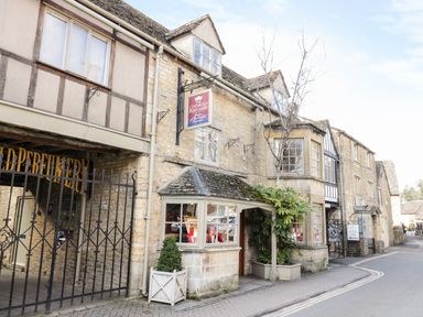 A street view of old stone buildings with a shop sign for The Cotswold Perfumery in Barnsley near Cirencester