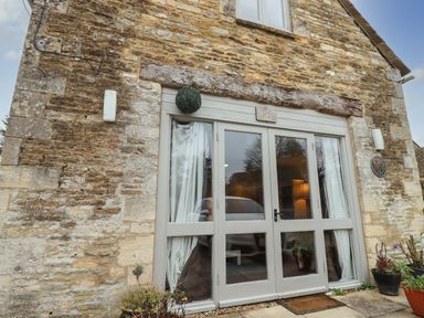 The exterior entrance with glass double doors and stone walls at Greyhound Barn Barnsley near Cirencester