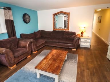 A living room with brown sofas wooden coffee table wall clock and a mirror at Greyhound Barn Barnsley near Cirencester