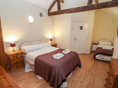 A bedroom with a double bed and a single bed with bedside tables and lamps at Greyhound Barn Barnsley near Cirencester