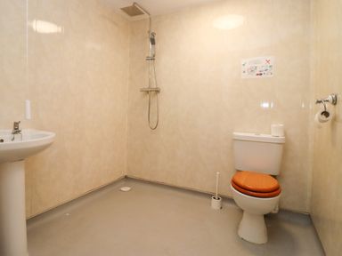 A bathroom with a toilet with a wooden seat a sink and a shower at Greyhound Barn in Barnsley near Cirencester