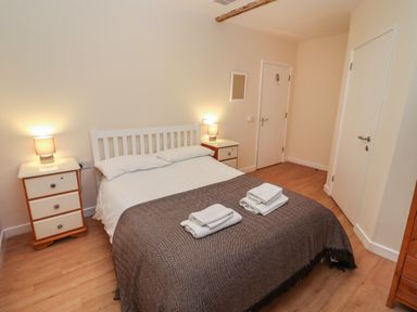 A bedroom with a bed two bedside tables and lamps at Greyhound Barn in Barnsley near Cirencester