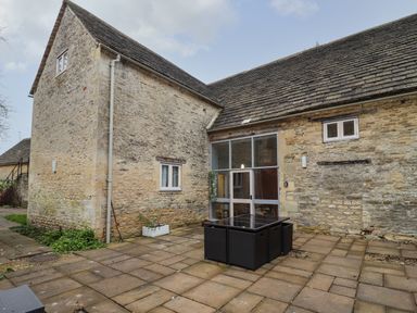 A stone courtyard with outdoor table and chairs at Greyhound Barn Barnsley near Cirencester