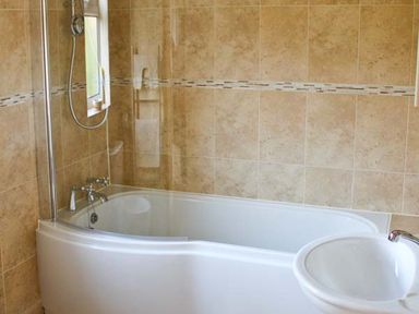 A bathroom with a bathtub shower combination and a sink at Moat Farm Cottage in Wood Dalling