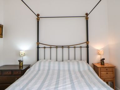 A bedroom with a metal framed bed and two bedside tables with lamps at Stable Cottage Belford near Bamburgh