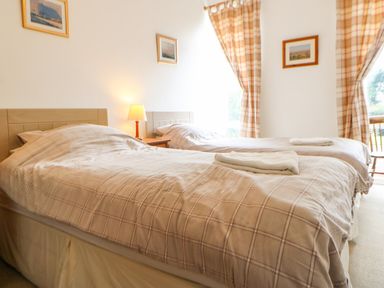 A bedroom with two single beds lamps and framed pictures on the wall at Stable Cottage Belford near Bamburgh