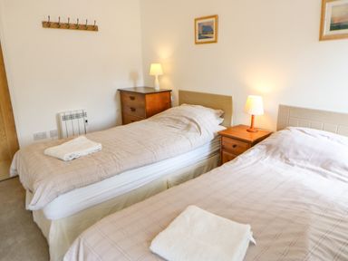 A bedroom with two single beds bedside tables and lamps at Stable Cottage Belford near Bamburgh