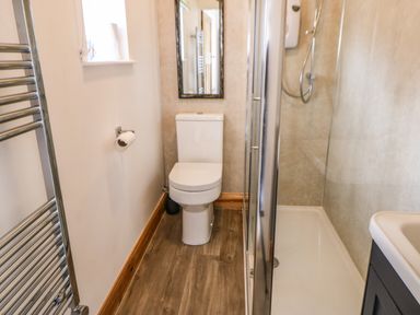 A bathroom with a toilet shower cubicle sink and towel rack at Stable Cottage in Belford near Bamburgh