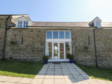 Stone building with two dormer windows and glass double doors at Mill Cottage in Aberaeron