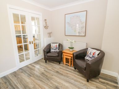 A small sitting area with two leather armchairs and wooden nesting tables between them at St Winifreds in Rhosneigr