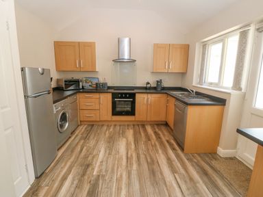 A kitchen with wooden cabinets appliances and a window at St Winifreds in Rhosneigr
