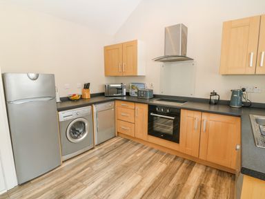 A kitchen with wooden cabinets stainless steel appliances and wooden flooring at St Winifreds in Rhosneigr