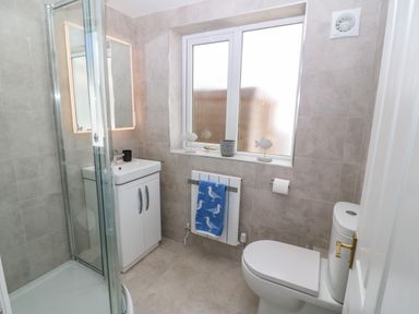 A bathroom with a shower enclosure sink cabinet toilet window and towel at St Winifreds in Rhosneigr