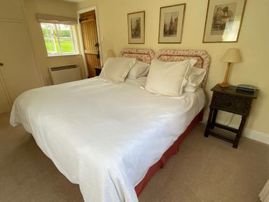 A bedroom with a double bed white bedding bedside tables lamps and framed pictures on the wall at Oke Apple Cottage in Okeford Fitzpaine