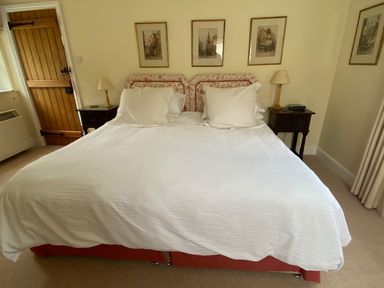 A bedroom with a double bed bedside tables with lamps and framed pictures on the walls at Oke Apple Cottage in Okeford Fitzpaine