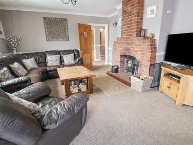 A living room with leather sofas wooden coffee table brick fireplace and television at Beach Cottage in Conwy