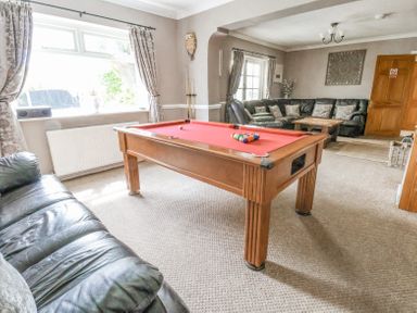 A living room with a pool table and sofas at Beach Cottage in Conwy