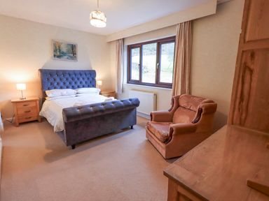 A bedroom with a bed and armchair at Ghyll Bank House Staveley near Windermere